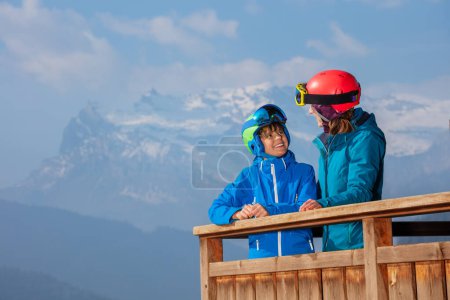 Foto de Dos compañeros de esquí hablan sonrisa en el balcón chalet, relajarse después de las pistas, con hermosos paisajes en el fondo - Imagen libre de derechos