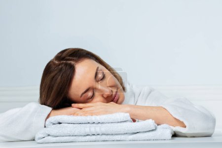 Téléchargez les photos : Gros plan portrait de beauté d'une femme en pleine forme, avec un sourire confiant dans l'avoine dormant calmement sur les serviettes de toilette - en image libre de droit