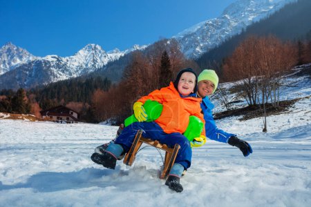 Téléchargez les photos : Deux enfants garçons, frères, glisser rapidement en descente et sur le point de tomber sur la pente alpine ensemble, des vacances d'hiver amusantes action - en image libre de droit