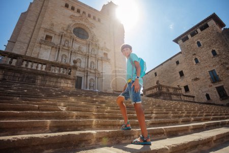 Téléchargez les photos : Adolescent beau garçon en excursion monter les célèbres escaliers de la cathédrale de Gérone lors de sa visite guidée en Espagne - en image libre de droit