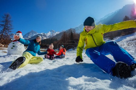 Foto de Joven familia rodar en la nieve en el campo soleado divertirse durante las vacaciones de invierno en el resort de montaña - Imagen libre de derechos