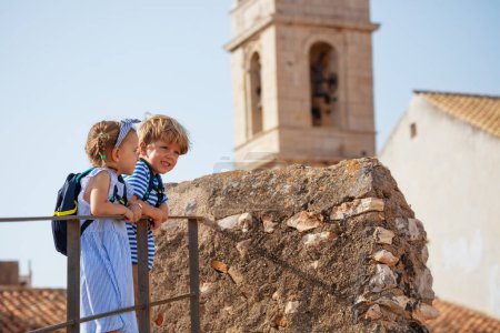 Téléchargez les photos : Enfants souriants, fille, garçon, touristes dans le château de Peniscola bénéficiant d'une vue imprenable et leur séjour en Espagne - en image libre de droit