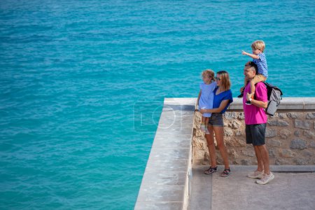 Téléchargez les photos : Famille touristique d'été en vacances stand à Peniscola mur regardant la belle mer Méditerranée et sourire, profiter de leur séjour en Espagne - en image libre de droit
