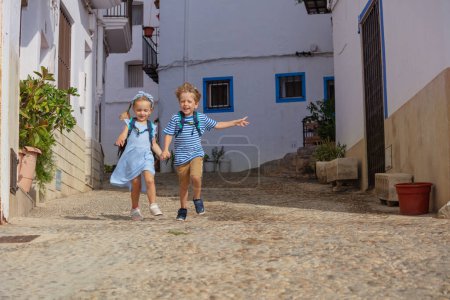Foto de Joven explorador chico, chica corriendo por las viejas calles de Peniscola, disfrutando del verano mediterráneo y de la arquitectura española - Imagen libre de derechos