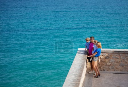 Foto de Familia turista de verano de vacaciones en la pared de la Peniscola mirando al hermoso mar Mediterráneo y sonreír, disfrutar de su estancia en España - Imagen libre de derechos