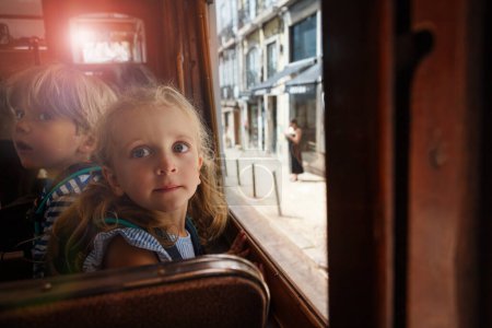 Foto de Dos niños pequeños se sientan en el famoso tranvía antiguo de Lisboa y dan un paseo cuesta arriba durante su viaje de verano en Portugal - Imagen libre de derechos