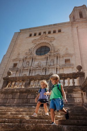 Téléchargez les photos : Deux mignons petit frère et sœur descendent les célèbres escaliers de la cathédrale de Gérone lors de leur voyage touristique en Espagne - en image libre de droit