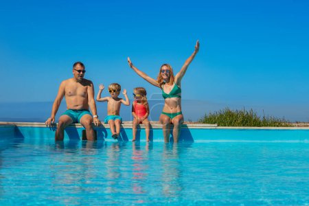 Foto de Familia feliz con niños y niñas disfrutando del tiempo juntos en la frontera de una piscina en un resort tropical - Imagen libre de derechos