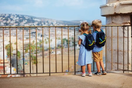 Téléchargez les photos : Deux touristes mignons, garçon, fille visitant l'Espagne profiter de la vue sur la plage, debout sur Peniscola point d'observation du château le jour ensoleillé d'été - en image libre de droit