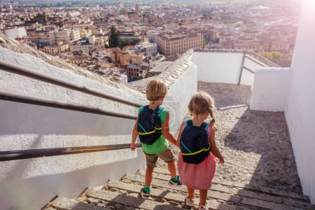 Téléchargez les photos : Les enfants touristes descendent les escaliers du point de vue de l'Alhambra ancien palais lors de leur voyage d'été à Grenade, Espagne - en image libre de droit