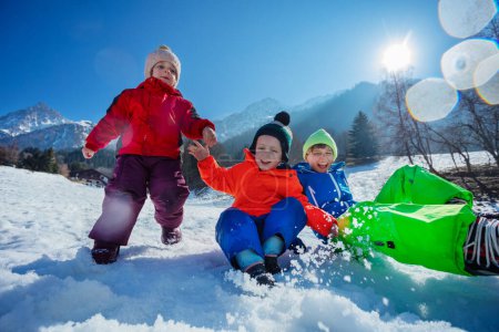 Téléchargez les photos : Heureux frères et sœurs sauter et rire dans la neige sur les sommets enneigés ensoleillés des montagnes profiter du camp d'hiver - en image libre de droit