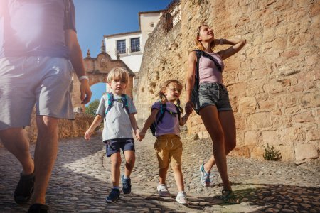 Foto de Familia de turistas con dos niños caminan por el casco antiguo de la soleada Ronda, disfrutan de su viaje europeo de verano en el sur de España - Imagen libre de derechos