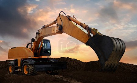 Foto de Wheeled excavator at work digging soil during sunset. - Imagen libre de derechos