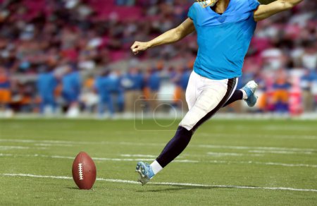 Foto de Jugador de fútbol americano pateando pelota en el campo del estadio - Imagen libre de derechos