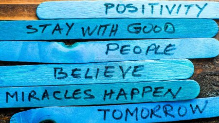 Gestapelte blaue Holzstäbe mit inspirierenden Botschaften über Positivität und Glauben
