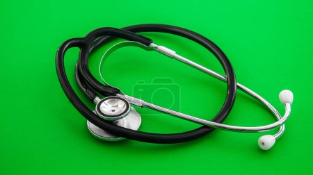 A stethoscope, indicative of the medical profession, is laid out on a pristine green  background