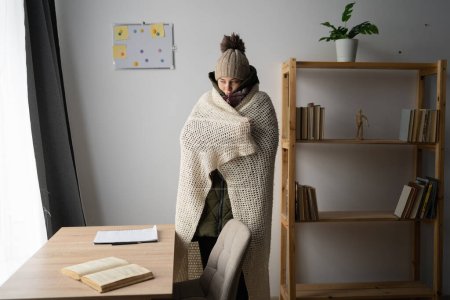 Photo for Angry girl student warmly dressed in a cold house suffering from cold at home, no heating and power concept - Royalty Free Image