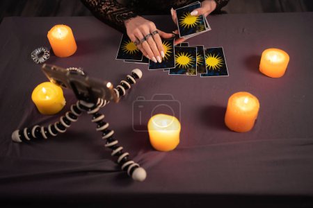 Photo for Fortune teller reading fortune lines on screen smartphone, online fortune telling application. Palmistry Psychic readings and clairvoyance concept with Tarot cards. Top view - Royalty Free Image