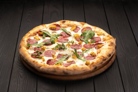 Classic Italian meat pizza with salami, cheese, arugula on a plate. Black background. Italian cuisine, selective focus. Copy pace