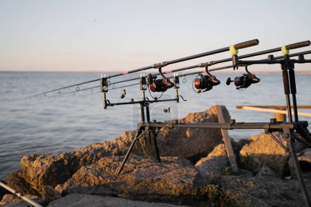 Photo for Spinning rods on a professional fishing rod stand outdoors on big stones - Royalty Free Image