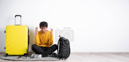 Téléchargez les photos : Glad positive traveler man crosses fingers, closes eyes with pleasure, anticipate hearing good news, isolated white background. Happy male wanted that his dreams come true. Excitement and travel fly - en image libre de droit