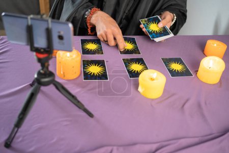 Photo for Fortune teller reading fortune lines on screen smartphone, online fortune telling application. Palmistry Psychic readings and clairvoyance concept with Tarot cards. Top view. Copy space - Royalty Free Image