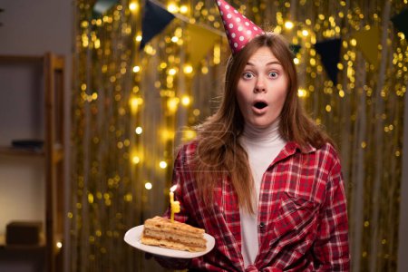 Téléchargez les photos : Young female celebrates birthday party at home, invites many friends for this special occasion, has shocked expression. Birthday girl with cake being surprised to see friend on party. copy space - en image libre de droit