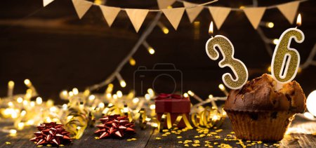 Téléchargez les photos : Number 36 birthday celebration candle in cupcake against lights and wooden background. Copy space. Banner - en image libre de droit