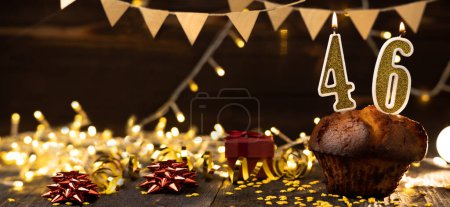Foto de Number 46 golden festive burning candles in a cake, wooden holiday background. forty-six years from the date of birth. the concept of celebrating a birthday, anniversary, holiday. Banner. copy space - Imagen libre de derechos