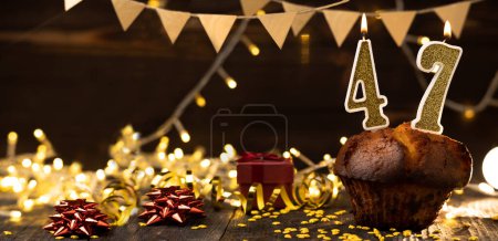 Foto de Number 47 golden festive burning candles in a cake, wooden holiday background. forty-seven years from the date of birth. the concept of celebrating a birthday, anniversary, holiday. Banner. copy space - Imagen libre de derechos