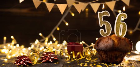 Photo for Number 56 golden festive burning candles in a cake, wooden holiday background. fifty-six years since the birth. the concept of celebrating a birthday, anniversary, holiday. Banner. copy space - Royalty Free Image