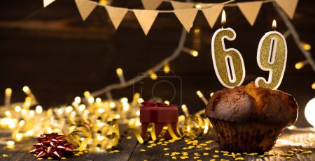 Foto de Number 69 golden festive burning candles in a cake, wooden holiday background. sixty nine years since the birth. the concept of celebrating a birthday, anniversary, holiday. Banner. copy space - Imagen libre de derechos