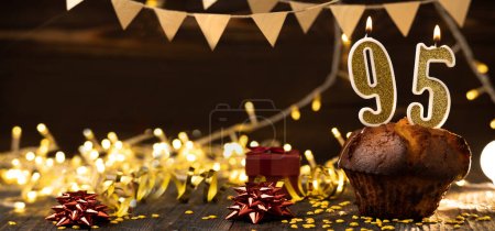 Foto de Number 95 golden festive burning candles in a cake, wooden holiday background. Ninety-five years since the birth. the concept of celebrating a birthday, anniversary, holiday. Banner. copy space - Imagen libre de derechos