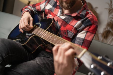 Photo for Man playing an acoustic guitar at home interior. Copy space - Royalty Free Image