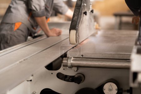 Téléchargez les photos : Menuisier dans une usine de meubles travaillant sur une machine à scier, gros plan. Espace de copie - en image libre de droit