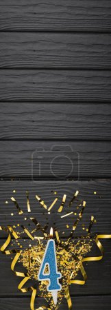 Téléchargez les photos : Number 4 blue celebration candle and gold confetti on dark wooden background. 4th birthday card. Anniversary and birthday concept. Vertical banner. Copy space - en image libre de droit