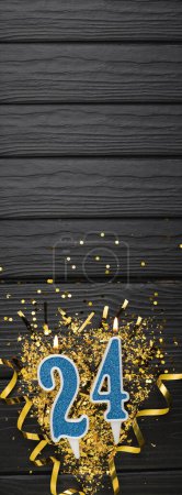 Téléchargez les photos : Number 24 blue celebration candle and gold confetti on dark wooden background. 24th birthday card. Anniversary and birthday concept. Vertical banner. Copy space - en image libre de droit