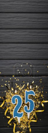 Téléchargez les photos : Number 25 blue celebration candle and gold confetti on dark wooden background. 25th birthday card. Anniversary and birthday concept. Vertical banner. Copy space - en image libre de droit