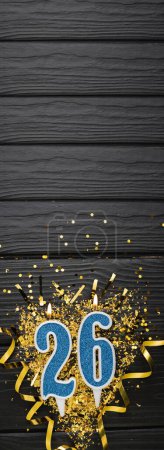 Téléchargez les photos : Number 26 blue celebration candle and gold confetti on dark wooden background. 26th birthday card. Anniversary and birthday concept. Vertical banner. Copy space - en image libre de droit