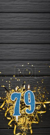 Photo for Number 79 blue celebration candle and gold confetti on dark wooden background. 79th birthday card. Anniversary and birthday concept. Vertical banner. Copy space - Royalty Free Image
