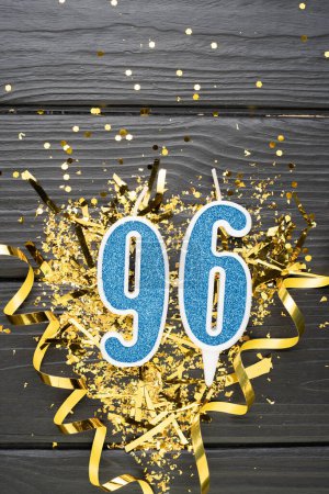 Foto de Vela de celebración azul número 96 y confeti dorado sobre fondo de madera oscura. Tarjeta de cumpleaños 96. Aniversario y concepto de cumpleaños. Banner vertical. Copiar espacio - Imagen libre de derechos