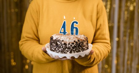 Foto de Mujer sosteniendo un delicioso pastel con el número 46 velas mientras se celebra la fiesta de cumpleaños. Concepto de fiesta de cumpleaños de la gente. De cerca. - Imagen libre de derechos