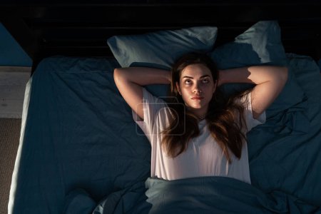 Téléchargez les photos : Stressé jeune femme au lit la nuit souffrant d'insomnie, vue de dessus. Fille éveillée déprimée couchée au lit et regardant au-dessus tard. Espace de copie - en image libre de droit