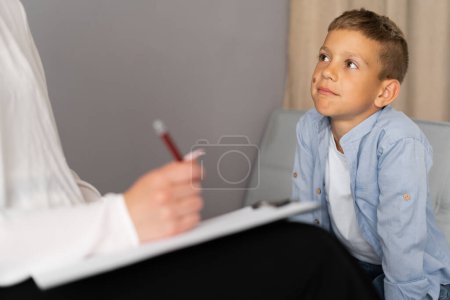 Professionelle Kinderpsychologin arbeitet mit kleinen Jungen im hellen Büro. Nahaufnahme