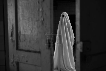 Photo for Ghost in a white sheet walking in an abandoned old house at night. Copy space - Royalty Free Image