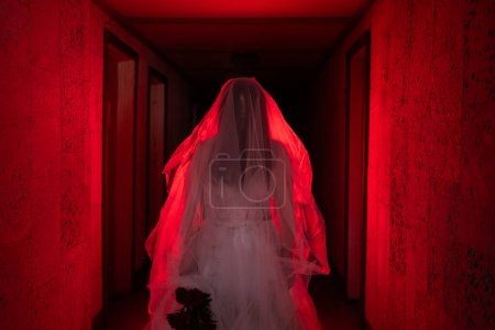 Escena de horror de una novia muerta parada en una casa embrujada con luz roja. Halloween concepto de celebración de miedo
