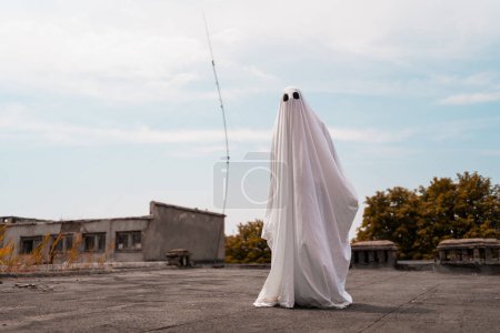 Photo for Ghost covered with a white ghost sheet on street. Halloween Concept. Copy space. - Royalty Free Image