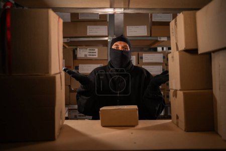 Photo for Thief caught red-handed in a warehouse with cardboard boxes, warehouse and store security concept. Copy space - Royalty Free Image