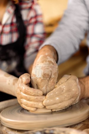 Photo for Potters hands guiding a woman hands to help her to work with the ceramic wheel. Copy space - Royalty Free Image