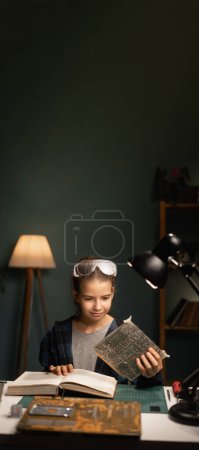 Photo for Schoolgirl soldering computer circuit with soldering iron and reading book in her room at home. Copy space. Banner - Royalty Free Image
